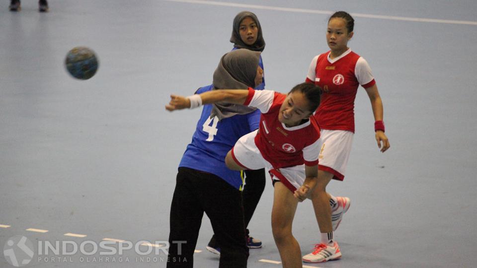 Pemain Putri Indonesia berhasil meloloskan diri dari hadangan pemain Malaysia dan mencetak angka.
